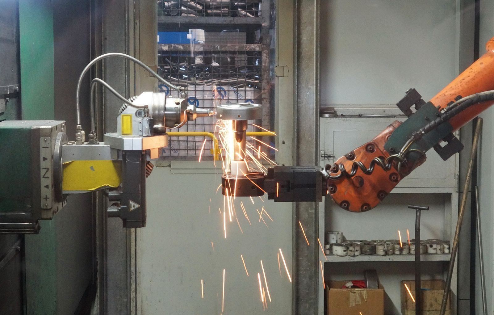 Robot industriel en cours d'usinage, projection d'étincelles